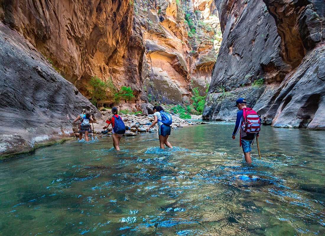 About Our Agency - Group of People Hiking Through a River at Zion National Park